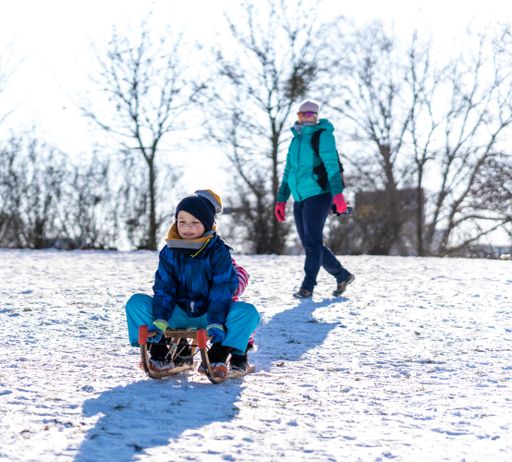 Young boy and girl sitting on a sled at a park on a cold day