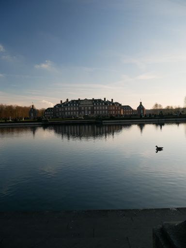 A vertical shot of a building's reflection in a lake