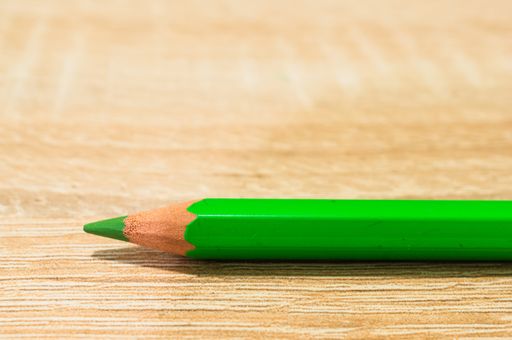 A closeup shot of a light green pencil on a wooden surface