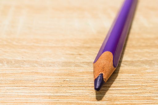 A closeup shot of a purple pencil on a wooden surface