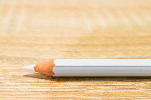 A closeup shot of a white pencil on a wooden surface