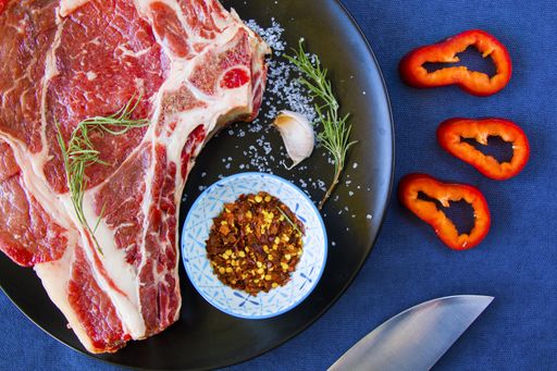 A plate of raw beef meat with spices and peppers