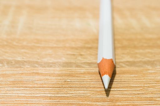 A closeup shot of a white pencil on a wooden surface