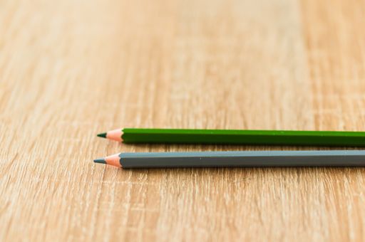 A closeup shot of two grey and green pencils on a wooden surface