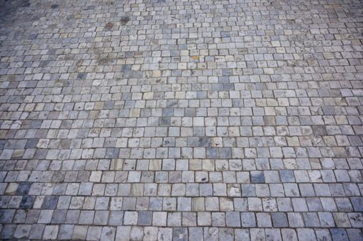 A high angle closeup shot of a cobblestone ground with grey square tiles