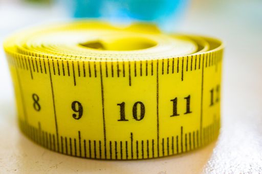A closeup shot of a yellow tape measure with a blurred background