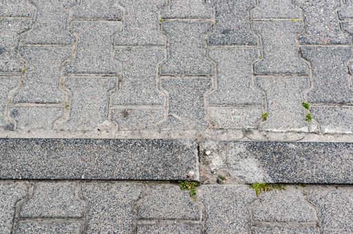 A closeup shot of the edge of a sidewalk with grey concrete tiles