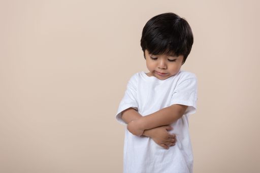 A young Hispanic boy posing for the camera with a sad expression on his face.
