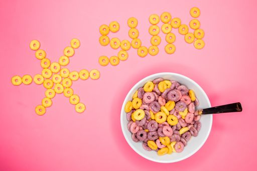 A top view of a cereal bowl with the cereal pieces aligned in a shape of a sun on pink background