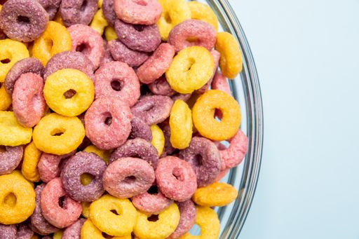 A closeup shot of breakfast cereal rings in a bowl isolated on a light blue  background