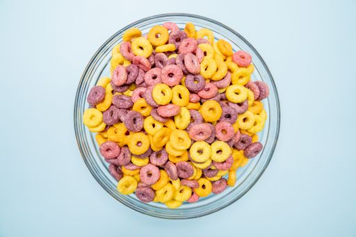 A top view of breakfast cereal rings in bowl isolated on blue background