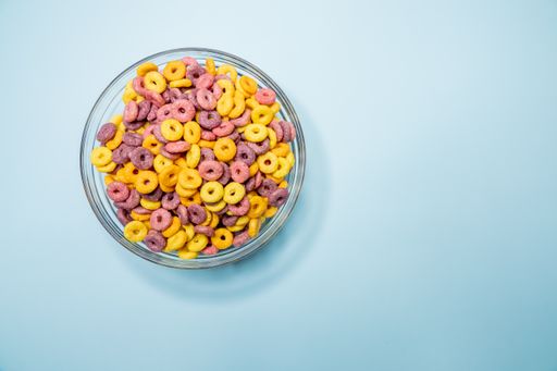 A top view of a bowl of colorful cereal on a blue surface under the lights