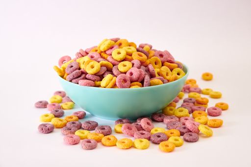 A closeup shot of multicolored fruity cereals in a blue bowl isolated on white background