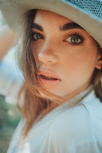 An attractive Bosnian Caucasian woman wearing a hat while looking at the camera with a serious face
