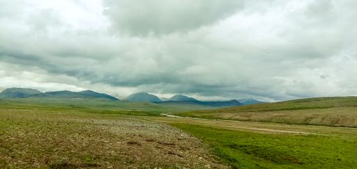 The dense clouds over a field and the mountains in the background