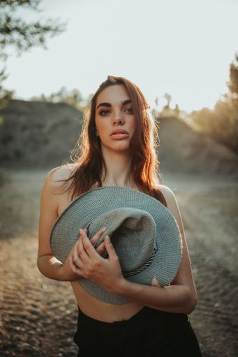 A portrait of a confident brunette female covering her chest with a stylish grayhat