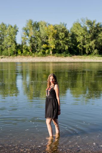 A vertical shot of a brunette female with red lipstick standing in the water