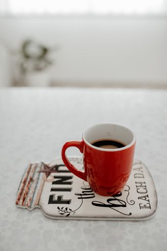 A vertical shot of a cup of hot coffee on a coaster