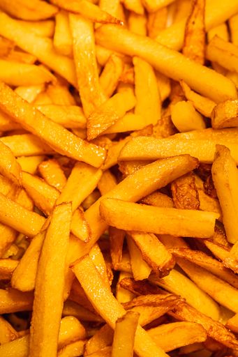Vertical shot of oily french fries potatoes background.