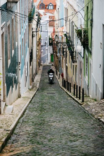 A vertical shot of a biker riding in the narrow street of Lisbon, Portugal