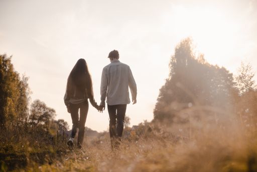 A back view of a young couple holding hands and climbing a hill