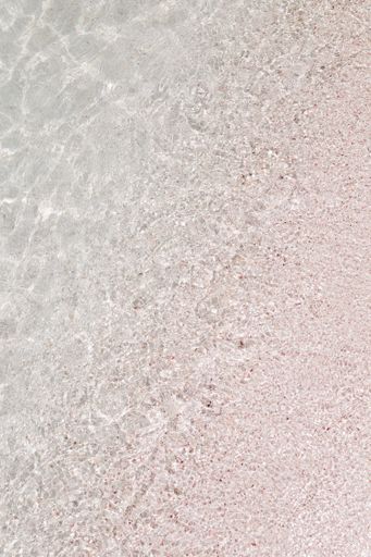 A vertical shot of a crystal clear wavy seashore with sa