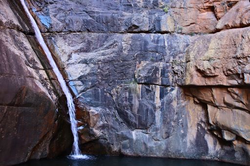 A waterfall flowing through a rock formation and pouring in the river