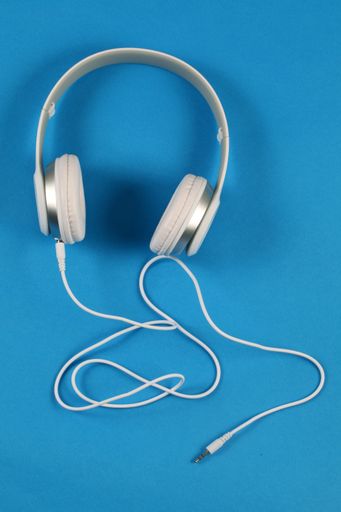 A vertical closeup shot of white headphones on a blue background