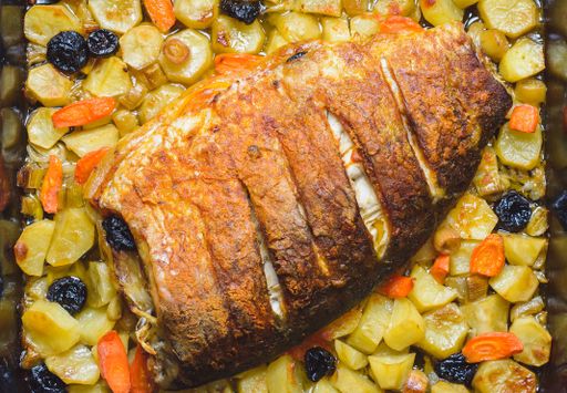 Close up shot of the fresh roasted tasty carp fish meat with dried plums, potatoes, leaks, onions, carrots and spices - ideal for food blog