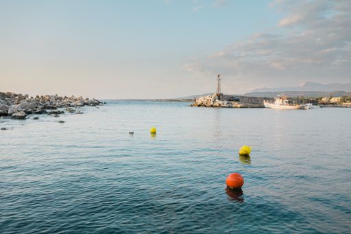 A beautiful shot of small buoys floating on the water with buildings on the shore