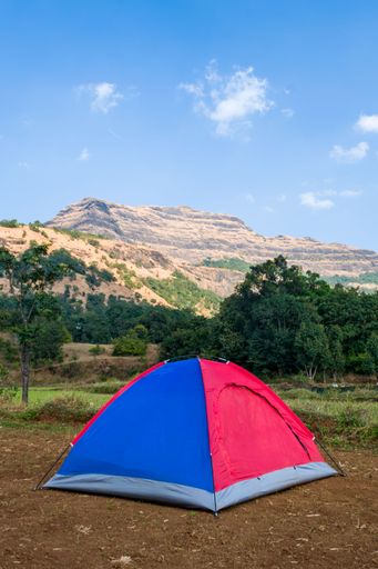 A beautiful landscape of camp and tents with hills in the background at Arthur Lake in Bhandardara in Maharashtra, India