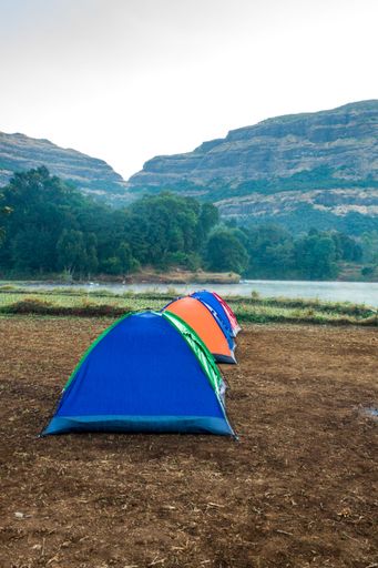 A beautiful landscape of camp and tents with hills in the background at Arthur Lake in Bhandardara in Maharashtra, India