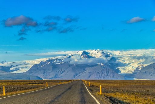 A closeup shot of an empty road surrounded by hills and fields in Iceland
