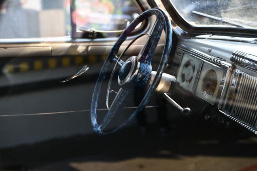 A selective focus shot of the steering wheel of a vintage car