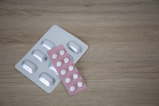 An overhead shot of a grey and pink lists of medicaments on the wooden surface