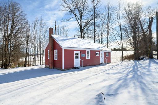 A beautiful red wooden house with a cloudy blue sky in the background on a sunny winter day