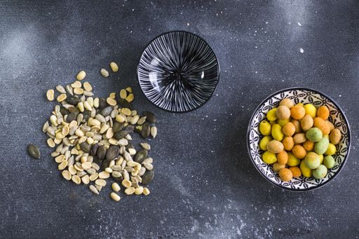 A top view of almonds, cashews and coasted nuts in bowls on the table