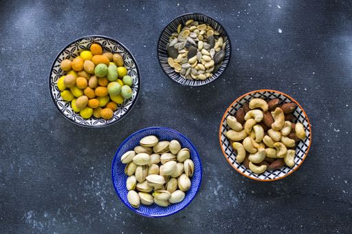 A top view of almonds, cashews and coasted nuts in bowls on the table