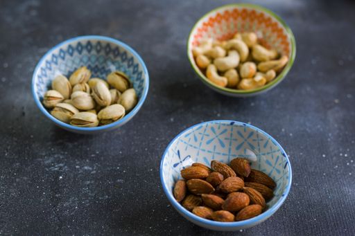 A closeup shoof almonds, cashews and coasted nuts in bowls on the table