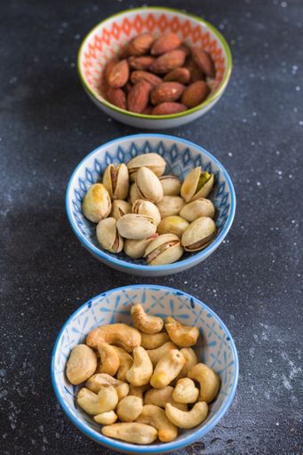 A vertical closeup shot of almonds, cashews and coasted nuts in bowls on the table