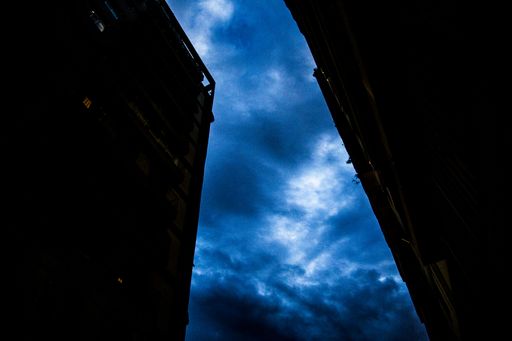 A bright blue sky between two dark buildings at night in Rio Brazil