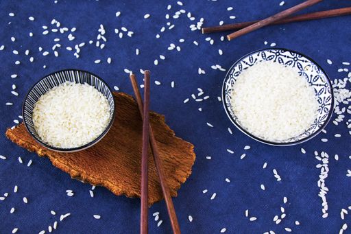 A high angle shot of rice with chopsticks on a blue surface