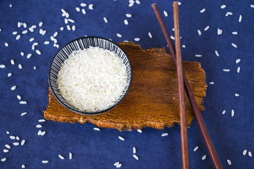 A high angle shot of rice with chopsticks on a blue surface