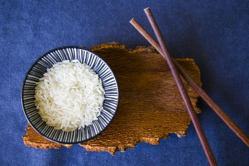 A top view shot of rice with chopsticks on a blue surface