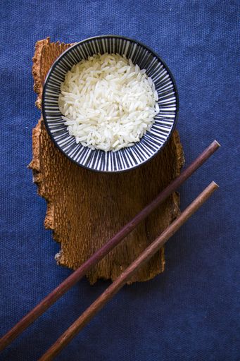 A top view shot of rice with chopsticks on a blue surface