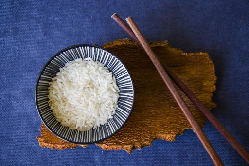 A top view shot of rice with chopsticks on a blue surface