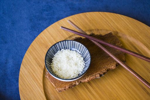 A high angle shot of rice with chopsticks on a blue surface