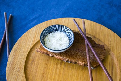 A high angle shot of rice with chopsticks on a blue surface