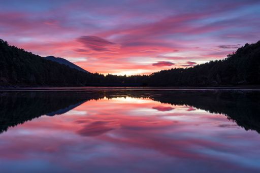 A scenic view of a beautiful twilight seen after sunset from the shore of a lake