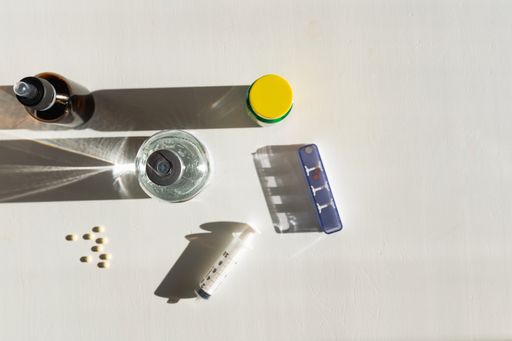 A top view of medicines, syringe, and solution on white background